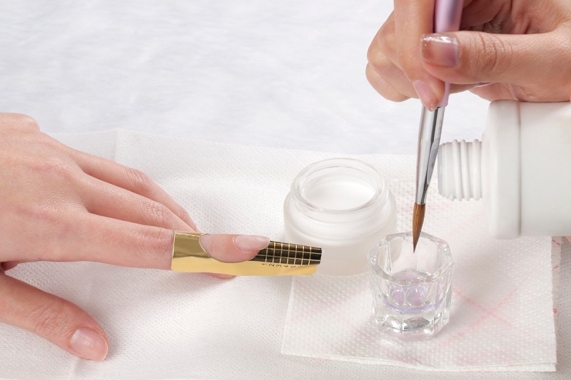 woman applying nail acrylic with monomer