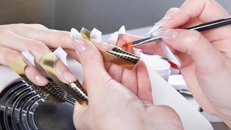 nail artist applying acrylic nails on a client